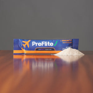 Single-serve PreFlite Airberry travel stick pack on a wooden surface with the berry hydration powder poured out beside it
